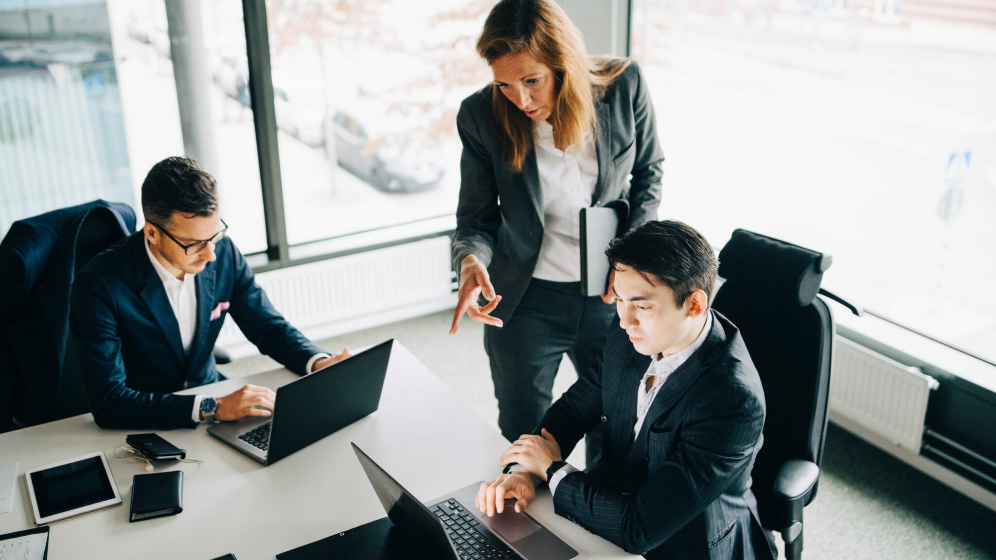 Gemischte Gruppe von Arbeitskolleg:innen die gemeinsam an Laptops arbeiten.